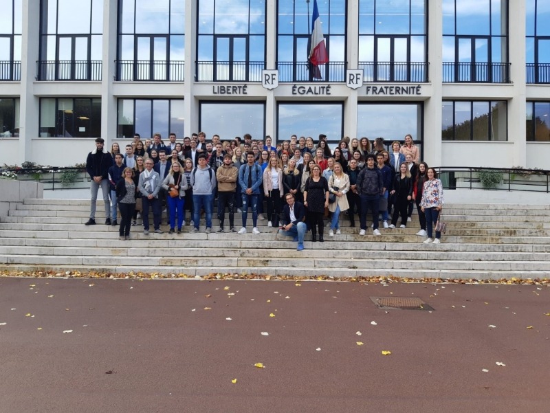 klasfoto van een zestigtal studenten op de trappen voor een gebouw in Frankrijk met de Franse vlag en leuze op.